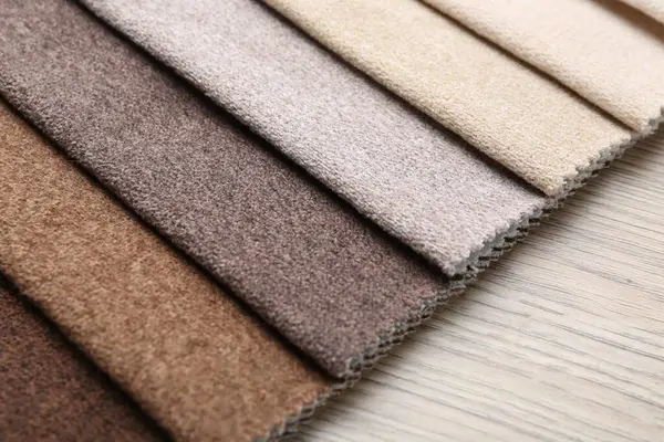 Tahta masadaki farklı kumaşlardan örnekler, yakın plan.