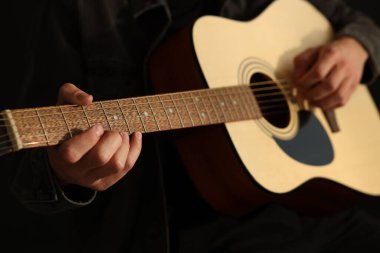 Siyah arkaplanda gitar çalan adam, yakın plan