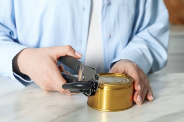 Beyaz mermer masada konserve açacağıyla konserve açan kadın, yakın plan.