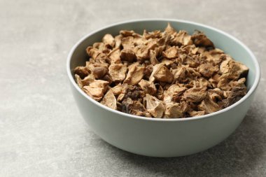 Kase içindeki kuru hindiba kökleri gri desenli masada, yakın plan.