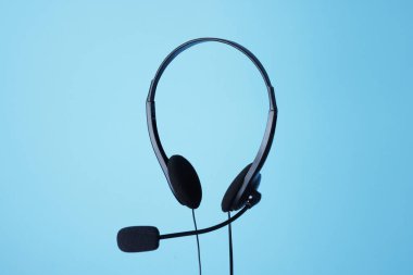 Açık mavi arka planda mikrofonlu kulaklık.