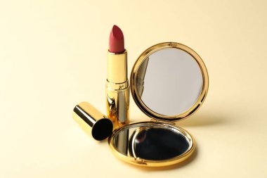 Bej arka planda cep aynası ve ruj izi, yakın plan.