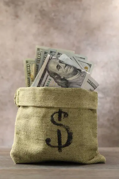 Tahta masanın üzerinde dolar banknotları olan çanta.