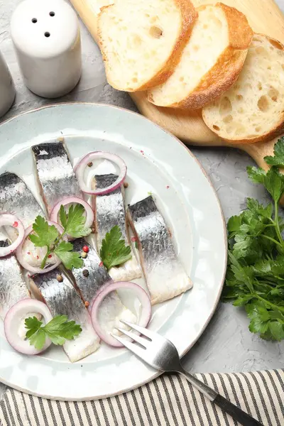 Gri desenli masada servis edilen baharat ve soğanlı lezzetli ringa balıkları.