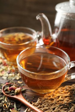 Bitki çayı ve kuru yaprakları ahşap masaya serpmek, yakın plan.