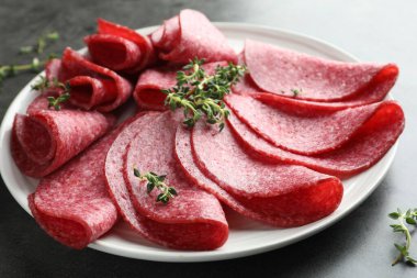 Gri masada servis edilen lezzetli sosis dilimleri, yakın plan.