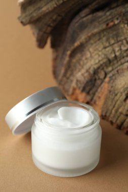 Bej arka planda bir kavanoz vücut kremi, yakın plan.