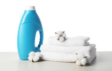 Beyaz arka planda bir şişe yumuşatıcı, pamuk çiçekleri ve havlular.