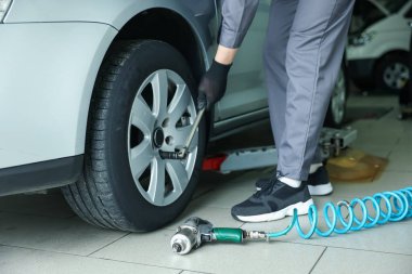 Tamirci araba servisinde lastik değiştiriyor, yakın plan.