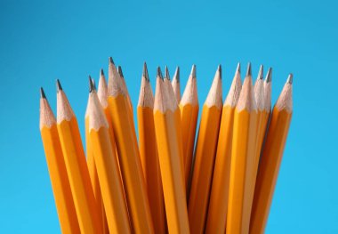 Açık mavi arkaplanda keskin grafit kalemler, yakın plan