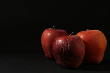 Siyah arka planda zarar görmüş kırmızı elmalar. Metin için boşluk