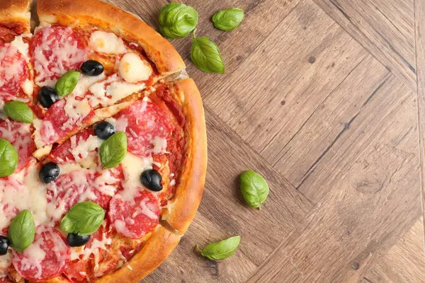 Tahta masada salamlı, peynirli, fesleğenli ve zeytinli lezzetli pizza. Metin için boşluk