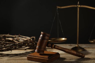 Hakimin tokmağı, terazisi ve dikenli tacı siyah arka plana karşı ahşap masada, yakın plan.