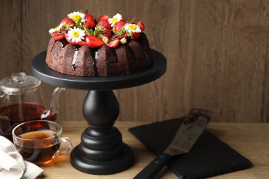 Çilekli çikolatalı kek, papatya çiçekleri ve ahşap masada çay.