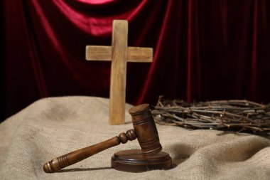 Yargıcın tokmağı, ahşap haç ve kırmızı perdeye karşı çuval bezi kumaşında dikenli taç.