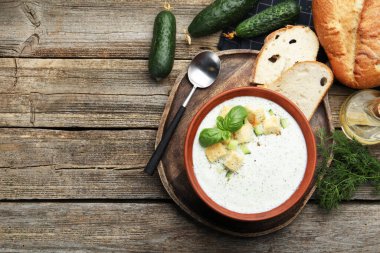 Tahta sehpada servis edilen kıtır kıtır salatalık çorbası ve fesleğen. Metin için boşluk