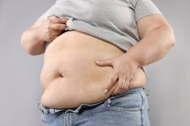 Gri arka planda aşırı göbek yağlı kadın, yakın plan.