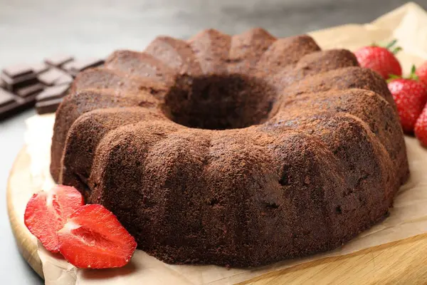 Lezzetli kek, çikolata parçaları ve gri masada çilekler, yakın plan.