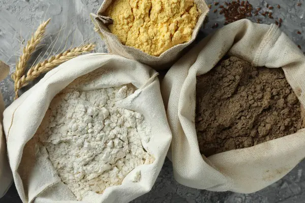 Gri desenli sehpada, düz yerde duran farklı tipte un var.