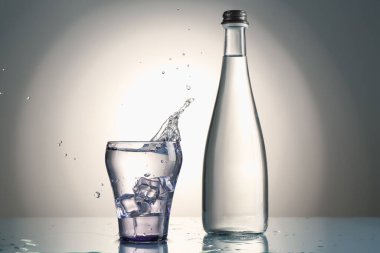 Tatlı su, cam parçalarından yansıyan gri arkaplana karşı ayna masasında.