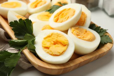 Beyaz masada haşlanmış yumurta ve maydanoz, yakın plan.