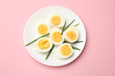 Pembe arka planda haşlanmış yumurta ve yeşil soğan.