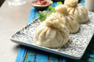 Lezzetli pişmiş khinkali gri masada servis ediliyor, yakın plan.