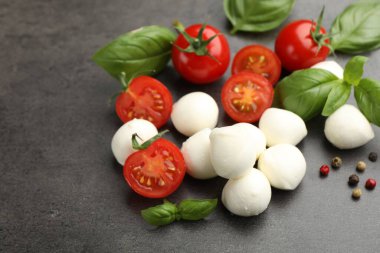 Mozzarella peyniri, domates, fesleğen ve biberler gri masada, yakın plan.