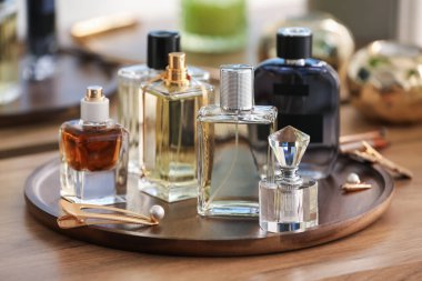 Farklı parfüm şişeleri ve aksesuarlar ahşap masada, yakın plan.