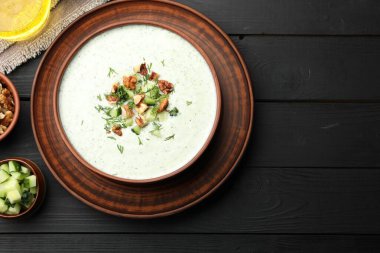 Siyah ahşap masada dereotlu ve cevizli lezzetli salatalık çorbası.