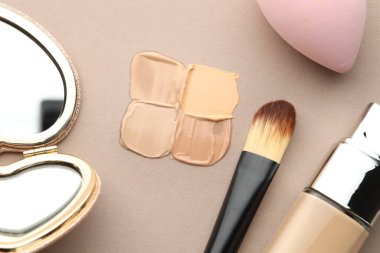 Renkli cilt temelleri ve gri arka planda makyaj fırçası, düz yatıyordu