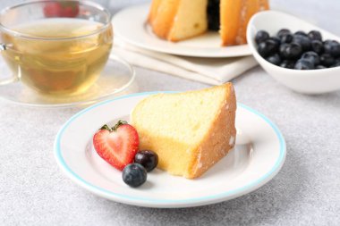 Açık gri masada böğürtlenli kek ve çay, yakın plan.