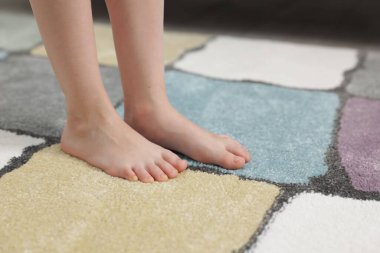 Evdeki yumuşak halıdaki kız, yakın plan.