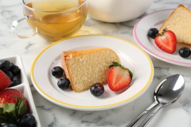 Lezzetli kek parçaları, böğürtlenli ve beyaz mermer masada çay, yakın plan.