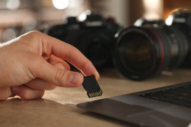 SD bellek kartını bilgisayarın içine yerleştiren adam ahşap masa, yakın plan