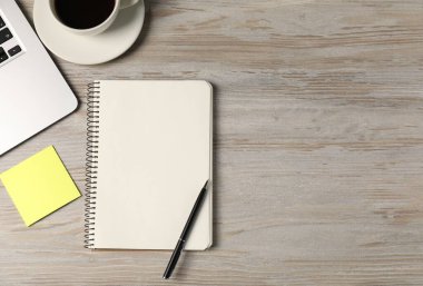 Defter, kalem, yapışkan not, sehpadaki kahve ve dizüstü bilgisayar, düz yatak. Metin için boşluk