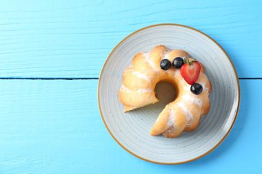 Açık mavi ahşap masa üzerinde pudra şekeri ve böğürtlenli Lezzetli Bundt keki. Metin için boşluk