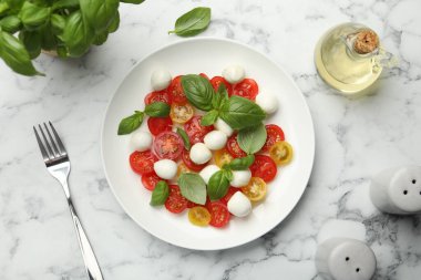 Beyaz mermer masada servis edilen mozarellalı, domatesli ve fesleğenli lezzetli salata.