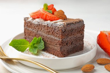 Çilekli, bademli ve naneli bir dilim lezzetli çikolatalı pasta.