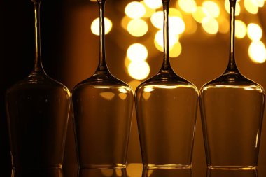 Bulanık ışıklara karşı cam ayna yüzeyinde birçok temiz bardak, yakın plan. Bokeh etkisi