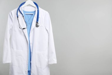 Gri arkaplandaki askıda steteskop olan doktorun ceketi. Metin için boşluk