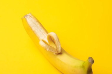 Sarı arka planda kabuktan yapılmış kalbi olan muz, yakın plan.