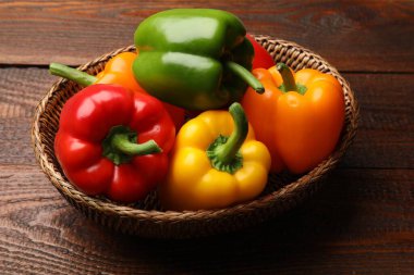 Taze renkli dolmalık biberler hasır sepetin içinde ahşap masanın üstünde, yakın plan.