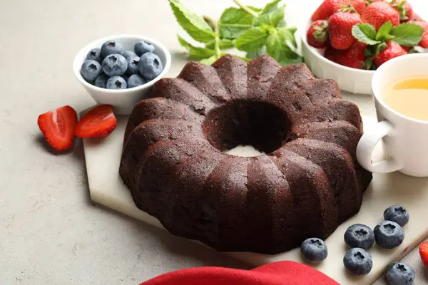 Lezzetli çikolatalı kek, çay ve böğürtlen ışık masasında, yakın plan.