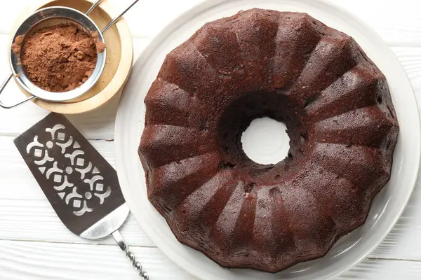 Lezzetli çikolatalı kek, kakao tozu ve beyaz ahşap masada servis, düz uzanma.