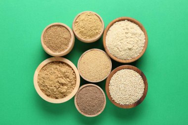 Yeşil arka planda kaselerde farklı süper yiyecek tozları var.