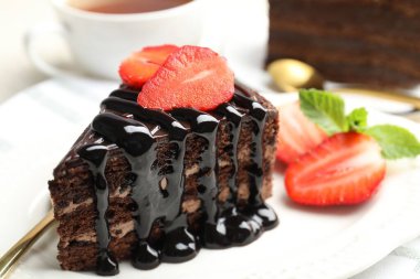 Bir parça çikolatalı kek. Masada çilek var. Yakın plan.