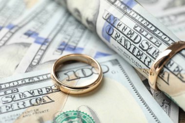 Altın alyanslar ve dolar banknotları, yakın plan.