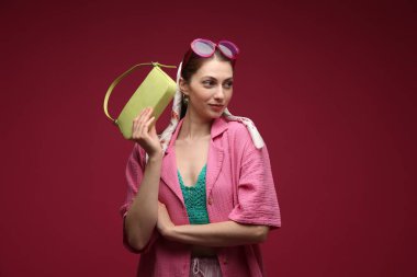 Koyu kırmızı arka planda şık giyinmiş güzel bir kadın portresi.