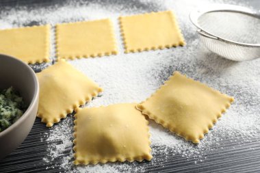 Pişmemiş ravioli, ahşap masaya doldurulmuş un, yakın plan.